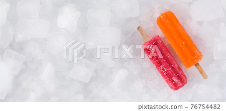 Orange and strawberry popsicles on ice cubes. Orange and strawberry popsicles on ice cubes. 76754482