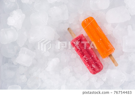 Orange and strawberry popsicles on ice cubes. 76754483