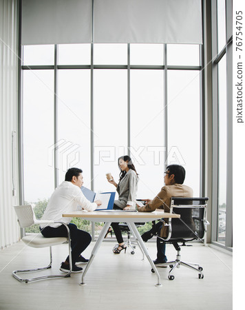 Asian businesswoman holding and looking at coffee cup  while manager and director discussing result 76754705