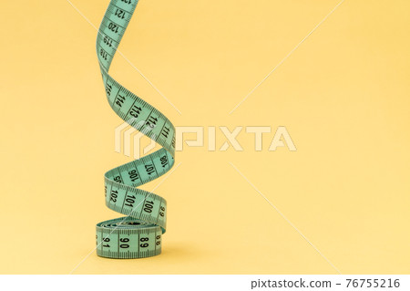 Measuring tape on yellow background Measuring tape on yellow background 76755216