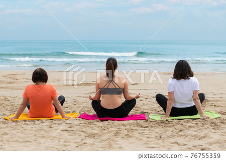 Three women relaxing and meditating at the beach Three women relaxing and meditating at the beach 76755359