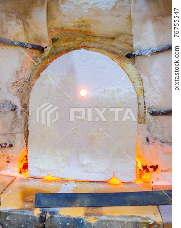 Shining glass blowing furnace behind cover. Gas kiln in glass design studio 76755547
