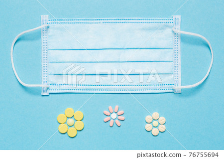 medical mask on a blue background and tablets are made in the form of flowers, concept allergy medical mask on a blue background and tablets are made in the form of flowers, concept allergy 76755694