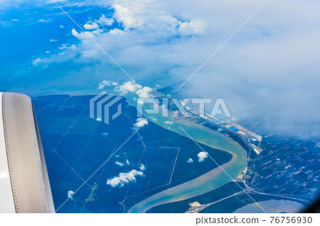 Landscape of fluffy white clouds on a dark blue sky with a part of an airplane. View from the plane at high altitude Landscape of fluffy white clouds on a dark blue sky with a part of an airplane. View from the plane at high altitude 76756930