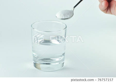 Baking soda, spoonful and glass of water. 76757157