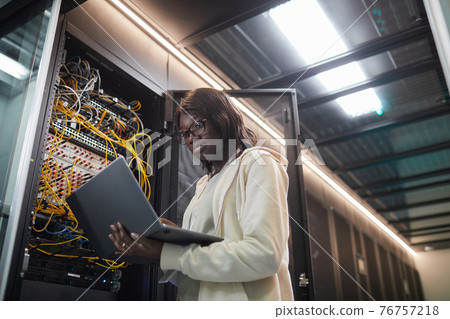 African American Woman Inspecting Servers in Data Center African American Woman Inspecting Servers in Data Center 76757218