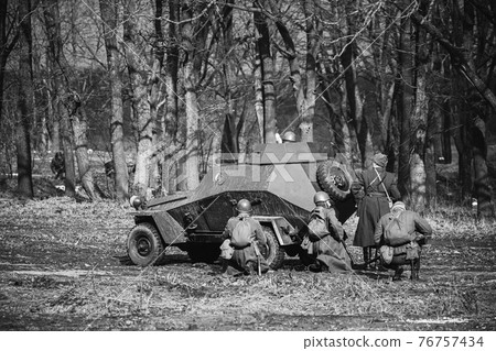 Group Of Reenactors Dressed As Russian Soviet Red Army Soldiers Of World War II Go On Offensive Under Cover Of Armored Soviet Scout Car. Historical Reenactment In Forest Group Of Reenactors Dressed As Russian Soviet Red Army Soldiers Of World War II Go On Offensive Under Cover Of Armored Soviet Scout Car. Historical Reenactment In Forest 76757434
