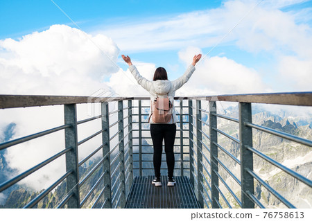 Tourist enjoying of amazing view of mountains and clouds. View from Lomnicky peak in Slovakia. Sport, hiking and active life concept. Tourist enjoying of amazing view of mountains and clouds. View from Lomnicky peak in Slovakia. Sport, hiking and active life concept. 76758613