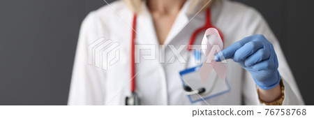 Doctor holding pink ribbon in his hand in rubber glove closeup 76758768