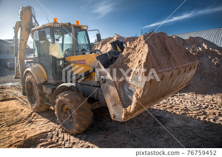 tractor with sand in the bucket on a clear day tractor with sand in the bucket on a clear day 76759452