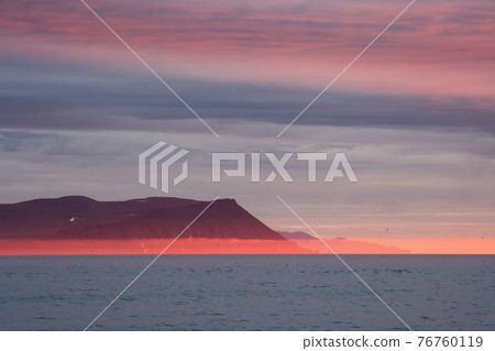 Amazing evening landscape of the coast of the Arctic Ocean with mountains, red fog and clouds at sunset. Amazing evening landscape of the coast of the Arctic Ocean with mountains, red fog and clouds at sunset. 76760119