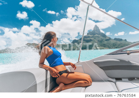 Luxury yacht travel woman enjoying ride on high end speed boat on summer vacation. Elegant bikini, long hair and sun tanned body. By famous Mount Otemanu, Bora Bora, French Polynesia, Tahiti 76763584