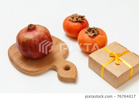 Ripe fresh pomegranate and persimmon fruits with cutting board. Ripe fresh pomegranate and persimmon fruits with cutting board. 76764817
