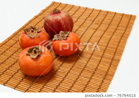 Ripe fresh pomegranate and persimmon fruits on bamboo napkin. Ripe fresh pomegranate and persimmon fruits on bamboo napkin. 76764818