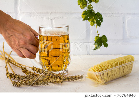 Glass of beer and potato chips on white background. Glass of beer and potato chips on white background. 76764946