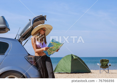 travel to the sea by car. the girl is looking for a road on the map. the car stopped on the beach travel to the sea by car. the girl is looking for a road on the map. the car stopped on the beach 76766898
