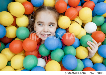 a child in the children's playroom. The girl is having fun among the colorful balls. Dry Pool Party a child in the children's playroom. The girl is having fun among the colorful balls. Dry Pool Party 76767006