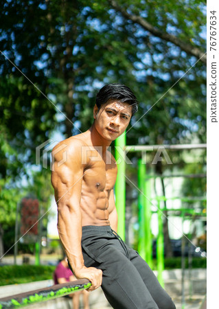 a naked Asian muscular man in a sitting pose and showing his muscular arms a naked Asian muscular man in a sitting pose and showing his muscular arms 76767634