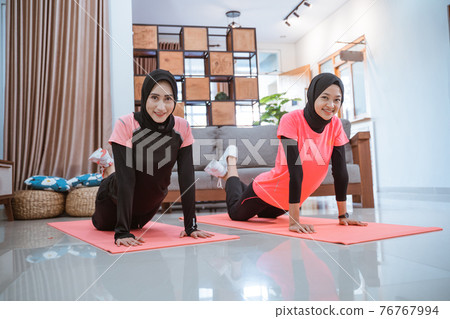 two women wearing hijab sportswear smile while doing push up two women wearing hijab sportswear smile while doing push up 76767994