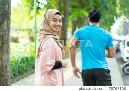 a girl in a veil smile looking at the camera when doing jogging together when outdoor exercise 76768108