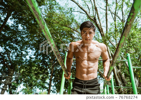 a handsome man doing pull ups to train stamina and back muscles a handsome man doing pull ups to train stamina and back muscles 76768274