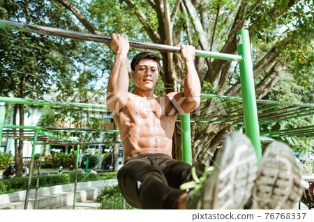 close up of an asian muscular man without clothes doing L pull-up exercises using iron bar 76768337