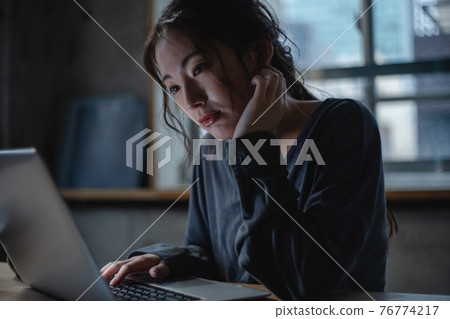 A woman staring at a computer while worried A woman staring at a computer while worried 76774217