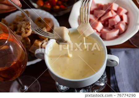 Cheese fondue with bread and snacks Cheese fondue with bread and snacks 76774290