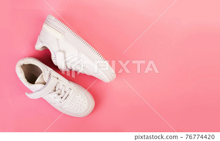 pair of white leather sneakers isolated on pink background pair of white leather sneakers isolated on pink background 76774420