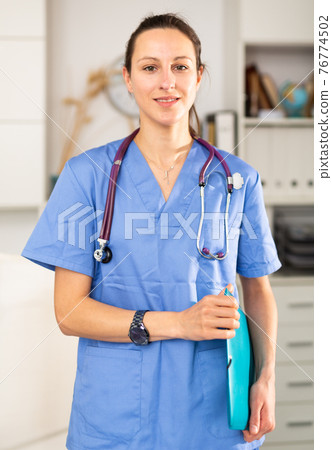 Young female doctor stands with a folder of documents in the office 76774502
