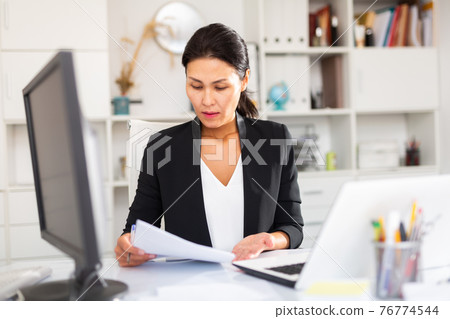 Adult business woman using laptop at workplace 76774544