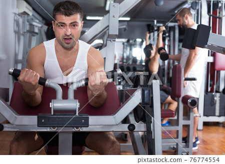Man training on fitness machine in gym Man training on fitness machine in gym 76774554