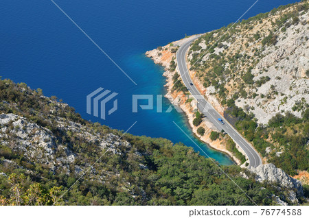 Aerial view of a winding coastal road and sea 76774588