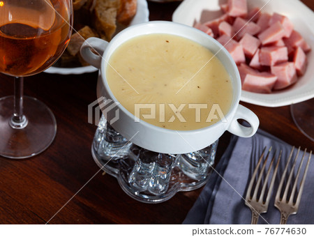 Cheese fondue with bread and sausages to dip Cheese fondue with bread and sausages to dip 76774630