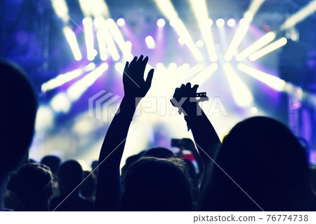 Crowd at a music concert, audience raising hands up 76774738