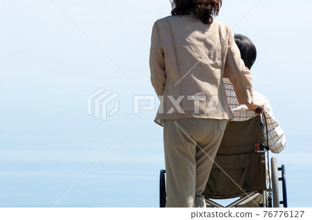 A couple taking a walk in a wheelchair A couple taking a walk in a wheelchair 76776127