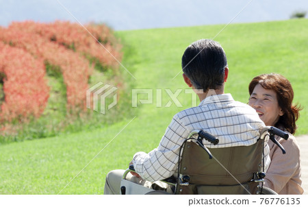 A couple taking a walk in a wheelchair 76776135