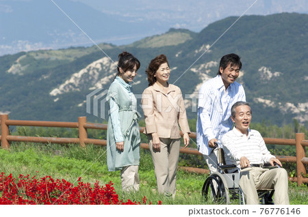 Senior man sitting in a wheelchair and a smiling family 76776146