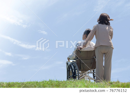 A couple taking a walk in a wheelchair 76776152
