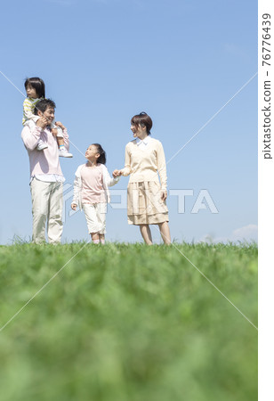 Family walking on the grass 76776439