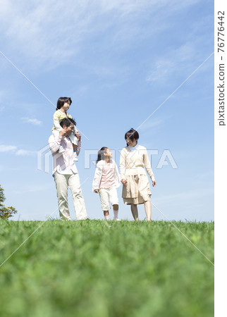Family walking on the grass 76776442