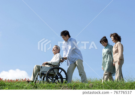坐在輪椅上的老人和一個微笑的家庭 76776537