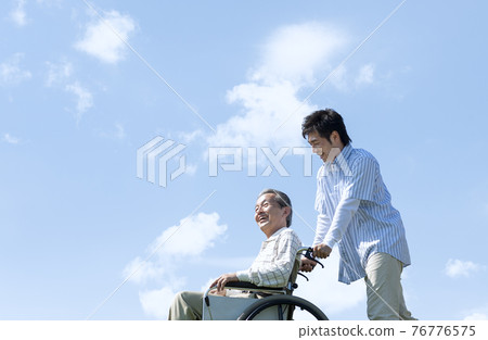 坐在輪椅和微笑的人的老人 76776575