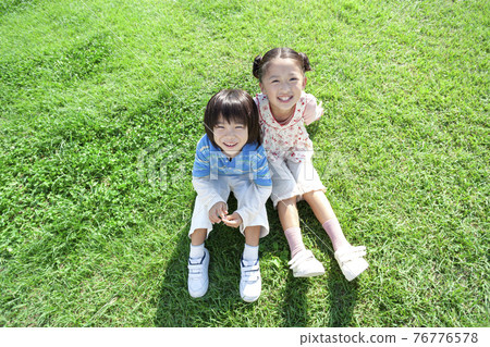 Girls and boys sitting on the lawn 76776578