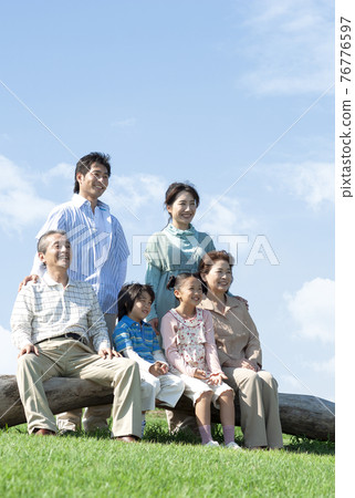 Three generation family sitting on a bench 76776597