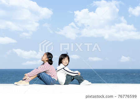 Girls and boys sitting on the breakwater 76776599