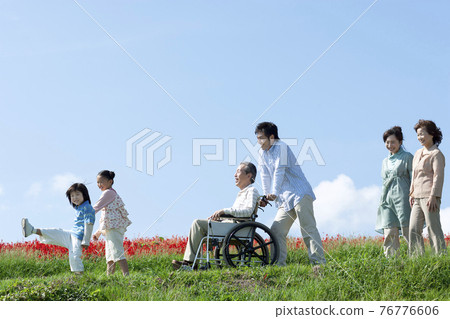 Senior man sitting in a wheelchair and a smiling family Senior man sitting in a wheelchair and a smiling family 76776606