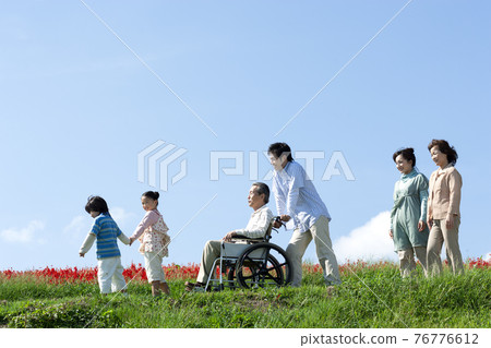 Senior man sitting in a wheelchair and a smiling family Senior man sitting in a wheelchair and a smiling family 76776612