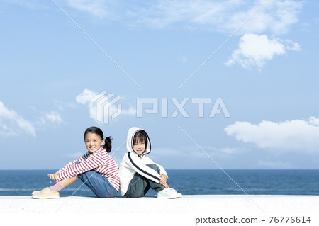 女孩和男孩坐在防波堤上 76776614