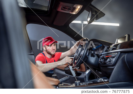 Man in overalls doing car maintenance Man in overalls doing car maintenance 76777875